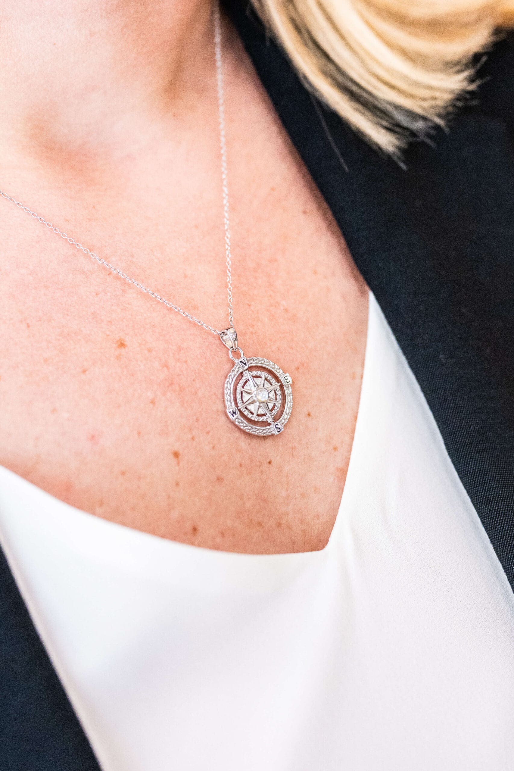 Details of a woman's compass necklace pendant on her chest