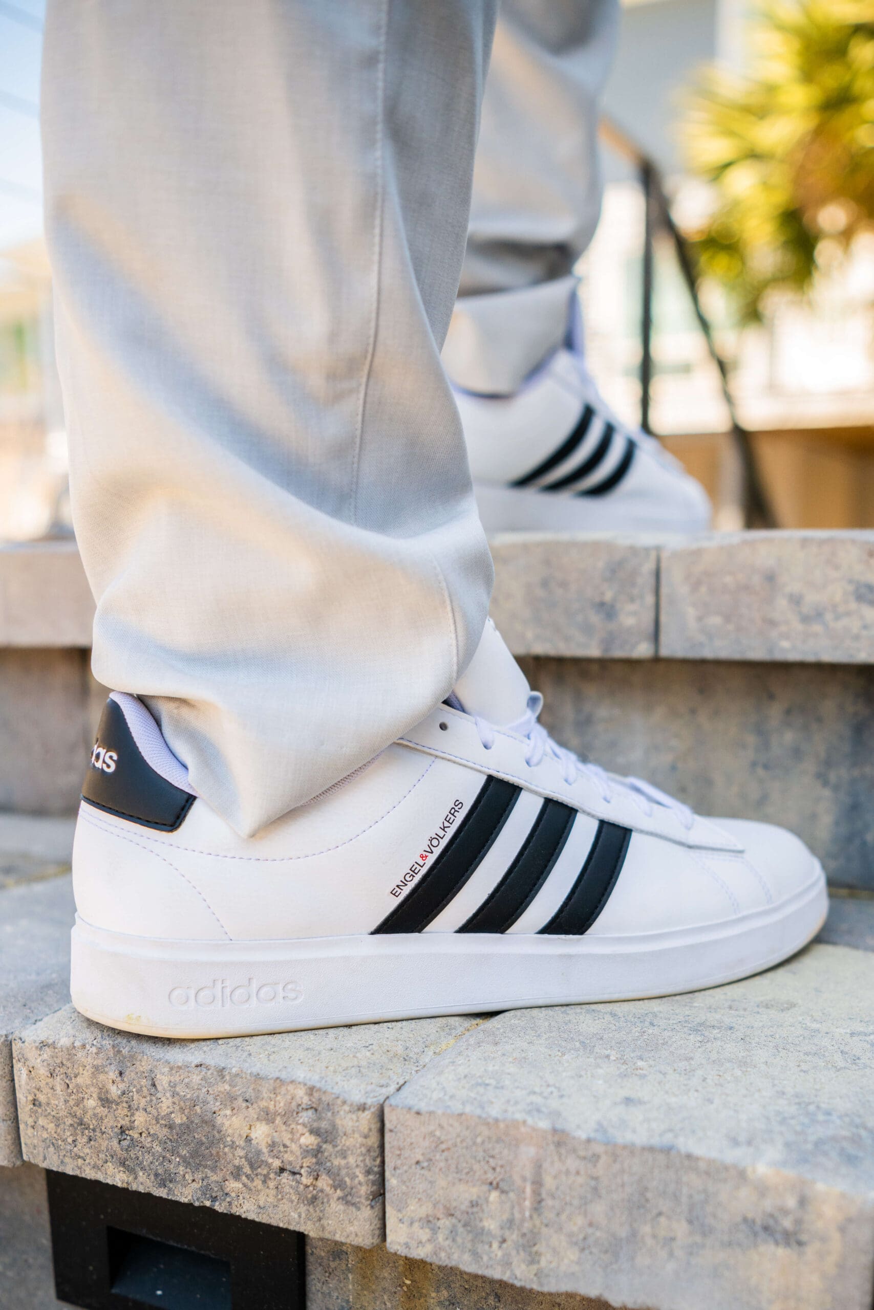 Details of a pair of white and black sneakers worn on cement steps