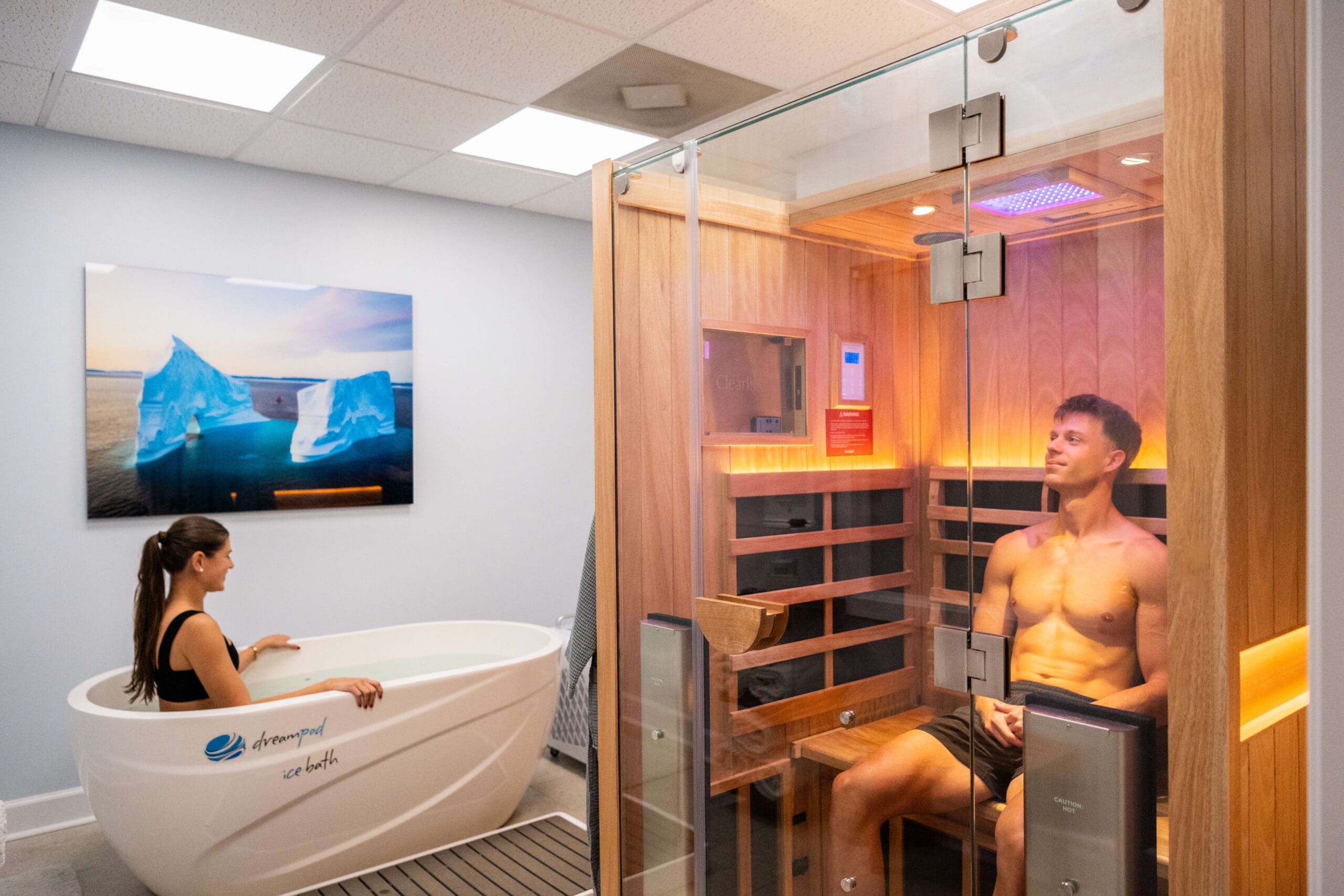 A man sits in a sauna while a woman enjoys an ice bath next to him at Compass Rose Health and Wellness