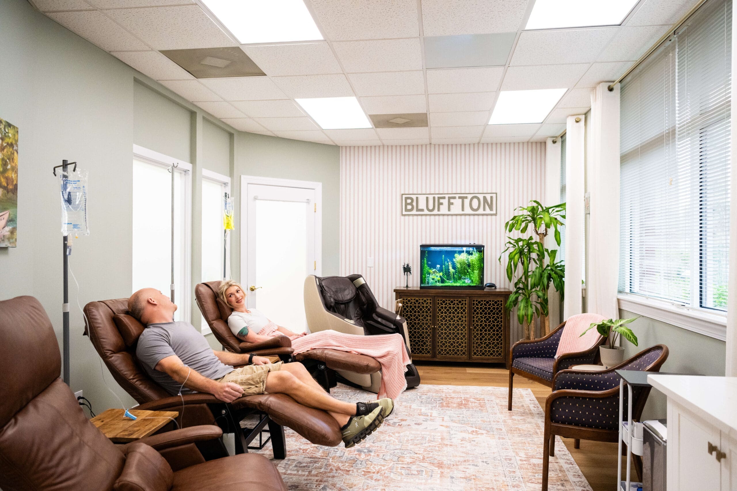 A man and woman lay in comfy leather chairs for an IV treatment at Compass Rose Health and Wellness