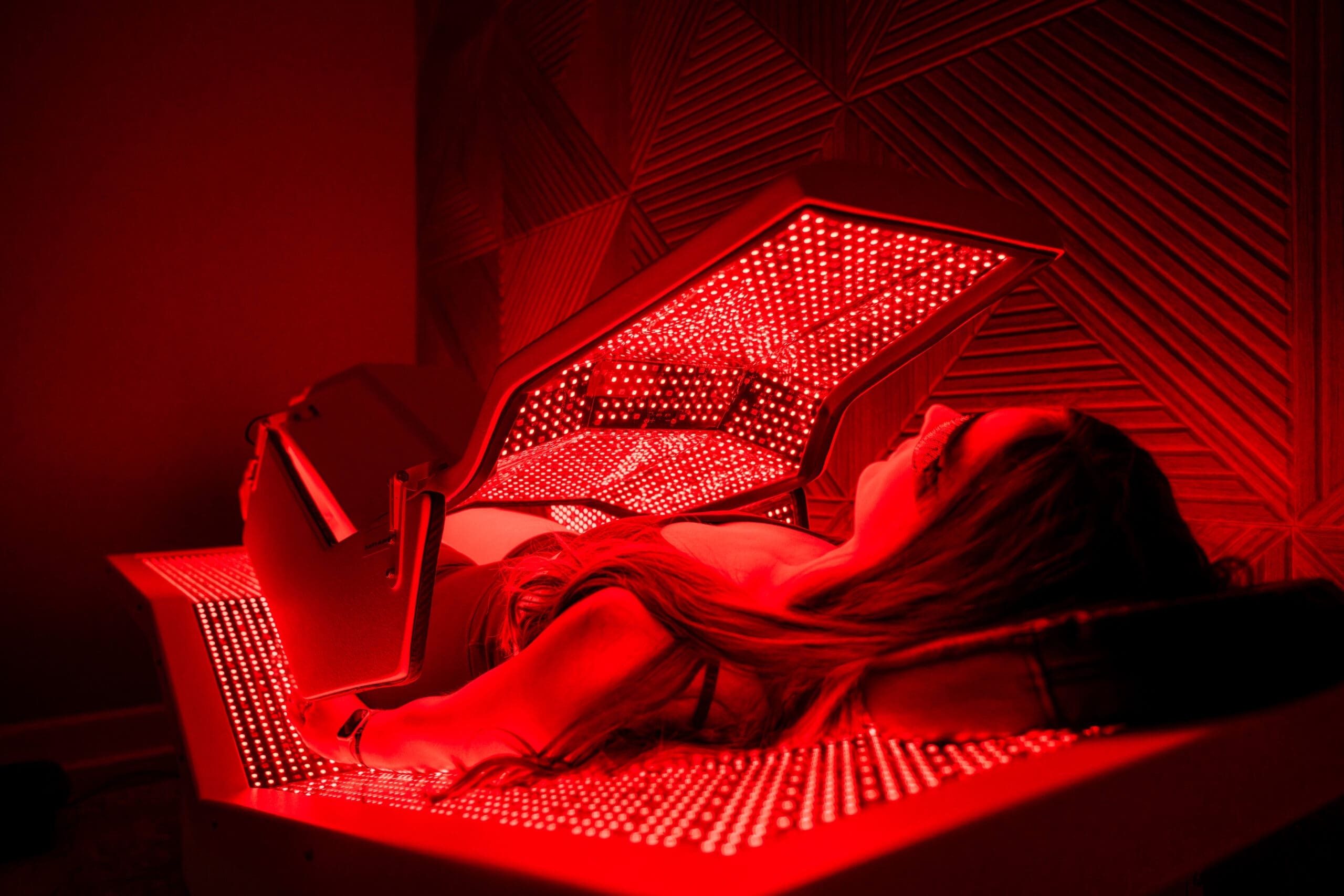 A woman lays in an infrared bed at Compass Rose Health and Wellness