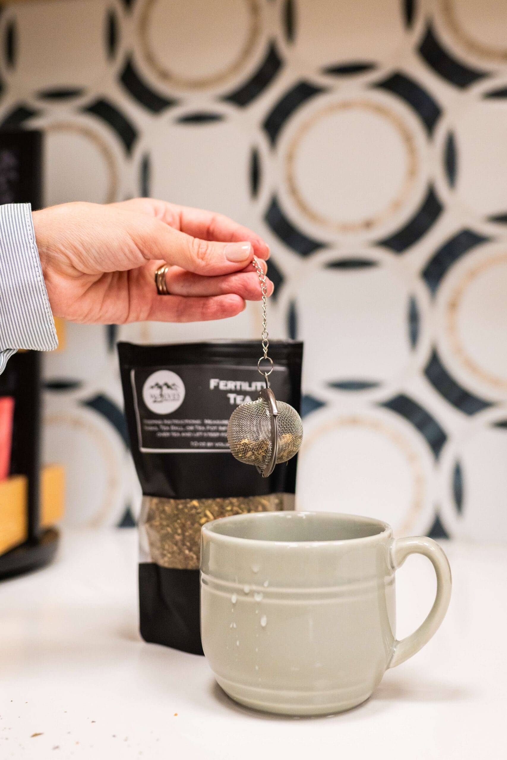 Details of a woman holding a tea diffuser over a cup and dry leaf for a campaign after business learned about Brand Photography vs Stock Photography
