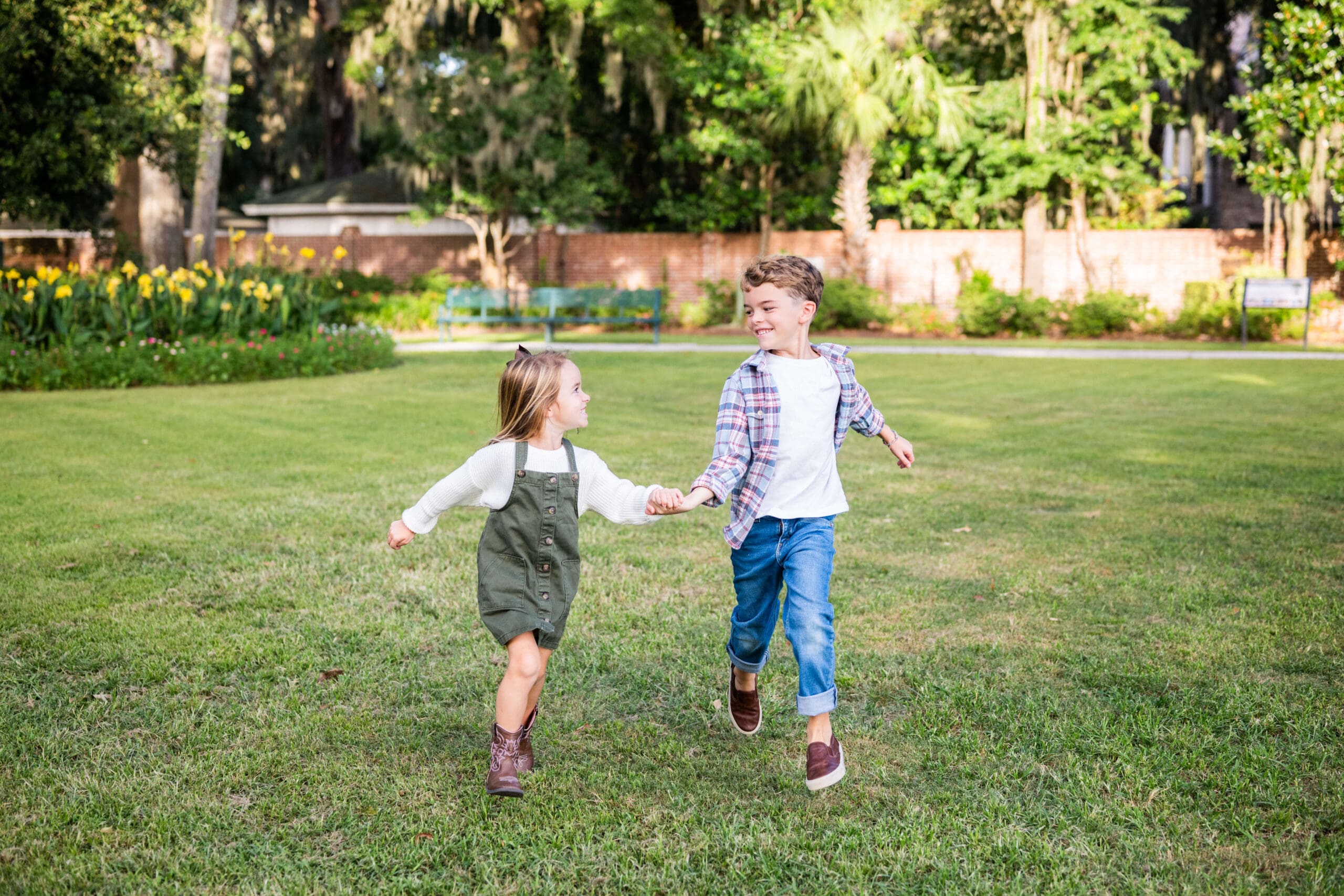 Young brother and sister run in a lawn holding hands and smiling at each other for a campaign after business learned about Brand Photography vs Stock Photography